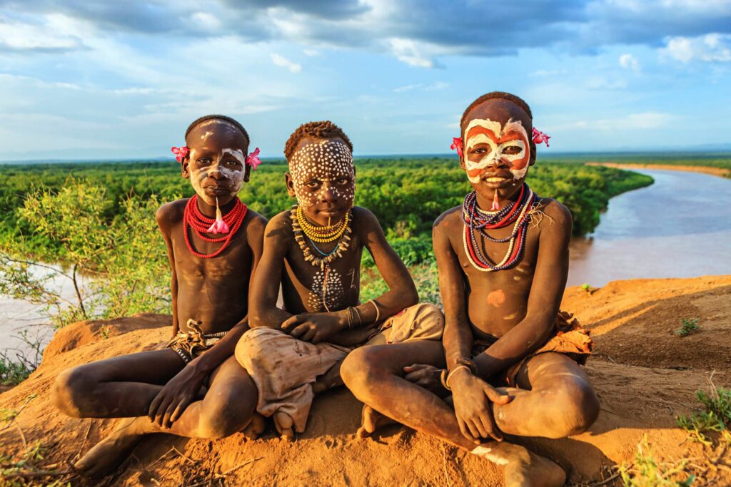 Three children donning traditional African attire and face paint